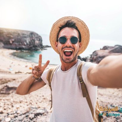 Young man with backpack taking selfie portrait on a mountain